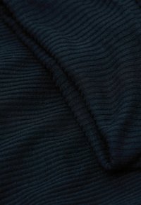 Tmavě modrá žebrovaná látka s jemnou texturou, zdobená úzkými, rovnoměrně rozloženými vertikálními pruhy, přeložená přes sebe pro větší hloubku a detail.