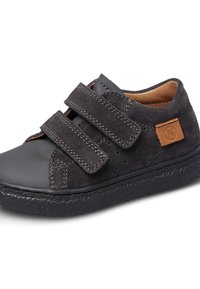 Zapato de ante negro con dos correas de velcro, detalle perforado y suela de goma texturizada. Presenta un acento de cuero marrón.