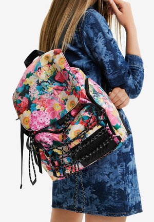 Sac à dos à motif floral avec une base rose vif, des accents noirs et plusieurs poches zippées. Sangles texturées et détails tissés.