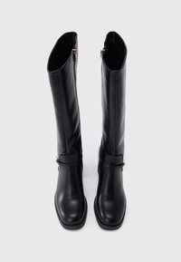 Μαύρες δερμάτινες μπότες μέχρι το γόνατο με λείο φινίρισμα, με χρυσές λεπτομέρειες φερμουάρ και λουράκι κοντά στον αστράγαλο.