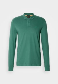 Polo cu mânecă lungă din bumbac verde, cu placket cu două butoane și un logo subtil pe piept. Textură moale, croială clasică.