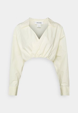 Blusa cropped amarelo claro com mangas longas, decote em V e cintura elástica; feita de algodão com uma textura suave. Etiqueta da marca visível.