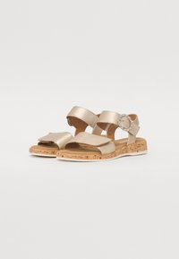 Gold metallic sandals with a cork sole, featuring two adjustable straps and a circular embellishment on the side.