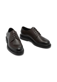 Pantofi din piele maro cu șiret, cu vârfuri rotunde, textură netedă și talpă din cauciuc negru în contrast. Design minimalist cu șase găuri pentru șireturi.