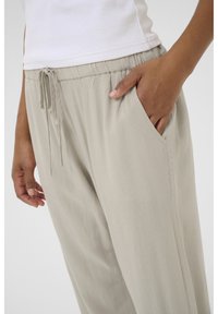 Light grey, wide-leg pants with an elastic waistband and drawstring, featuring side pockets and a soft, textured fabric.
