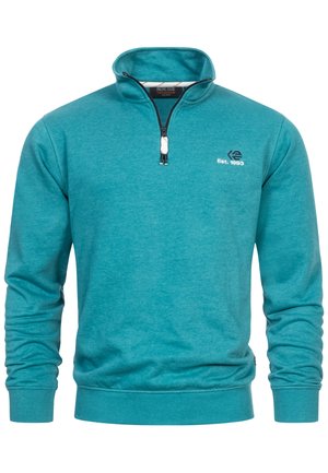 Teal tröja med kvartdragkedja i halsen, långa ärmar, en logotyp på bröstet och ribbade muddar och nederkant. Tillverkad av mjukt, texturerat material.