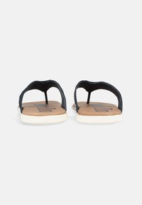 Mörkblå flip-flops med en tappdesign, med en brun dämpad sula och vit gummisula. Inga synliga mönster eller utsmyckningar.