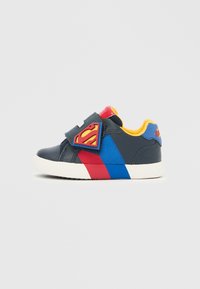 Sötétkék tépőzáras sportcipő piros és kék részletekkel. Superman logóval ellátott folttal és sárga belsővel. Gumi talp.