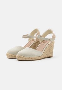 Wedges de espadrille color beige claro con parte superior de lona, tacón envuelto en yute, correa elástica en el tobillo y detalle texturizado en la parte posterior.
