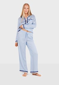 Blue patterned pajama set with a collared top and elastic waistband pants, featuring dark blue accents on cuffs and hem. Soft fabric texture.