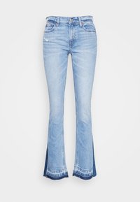 Jeans de mezclilla azul claro con campana y dobladillo deshilachado, que presentan un pequeño desgarrón en la parte delantera y acentos azul oscuro en la parte inferior de las piernas.