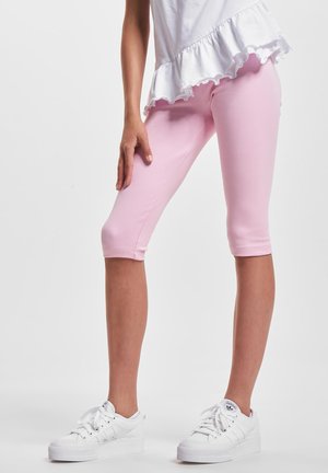 Leggings capri rosas hechos de un material elástico, con un diseño ajustado y una cintura elástica. Combinados con zapatillas blancas.