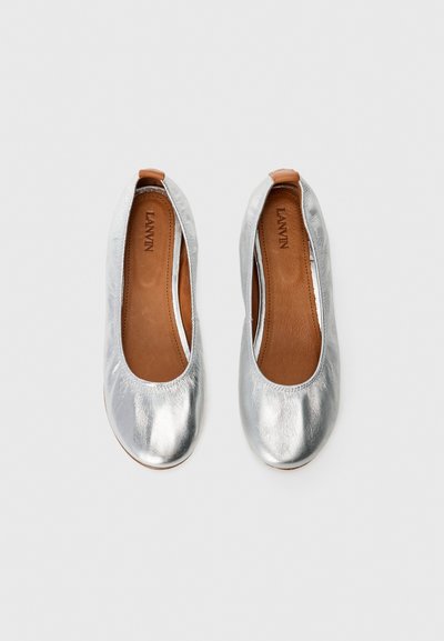 Zilveren metallic balletschoenen met een gladde afwerking, ronde neuzen en een leren bruine binnenzool. Minimalistisch ontwerp, instapstijl.