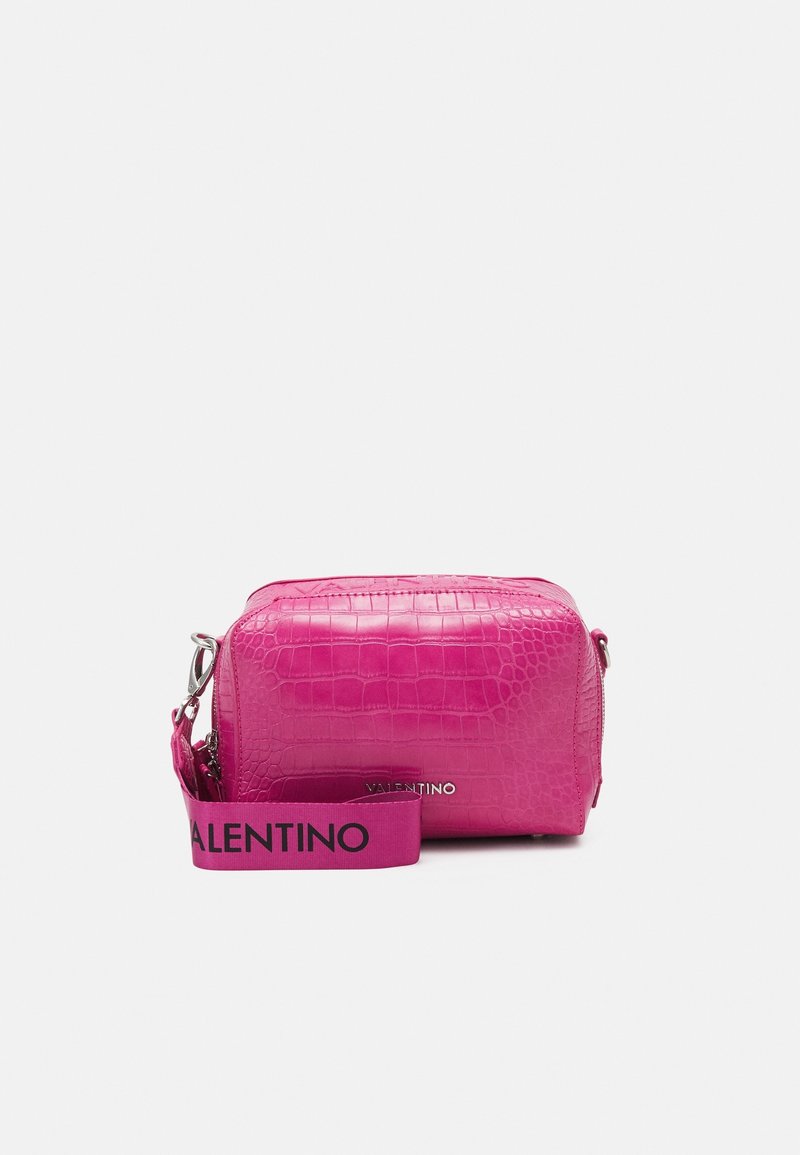 Kožená taška horké růžové barvy s krokodýlím vzorem a obdélníkovým tvarem. Má stříbrný zip a látkový popruh s nápisem "VALENTINO" v černé barvě.