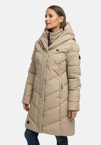 Beige polstret frakk med høy krage og hette, med skrå sømmer og to sidelommer, laget av et glatt og slitesterkt stoff.