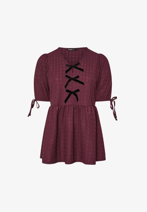 Pflaumenlila strukturierte Bluse mit Puffärmeln, drei schwarzen Samtbowties auf der Vorderseite und Bindebändern an den Ärmelbündchen.