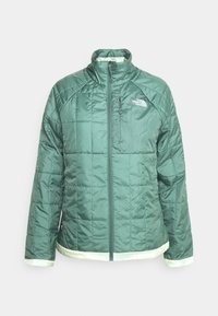 Zelená prošívaná bunda s vysokým límcem; má plný zip, prošívanou texturu a kontrastní světle zelený lem na spodním okraji a rukávech.