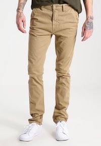 Benvita bomullschinos med slim fit, med dragkedja, bältesstygon och sidofickor, matchat med vita sneakers.