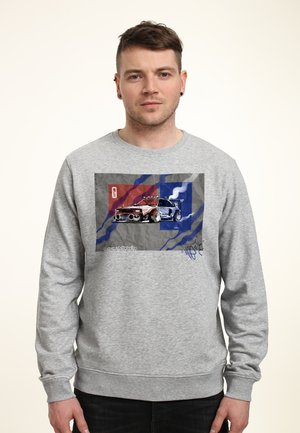 Felpa grigia con stampa grafica di una macchina da corsa su uno sfondo texturizzato con accenti rossi e blu. Polsini e orlo a coste.