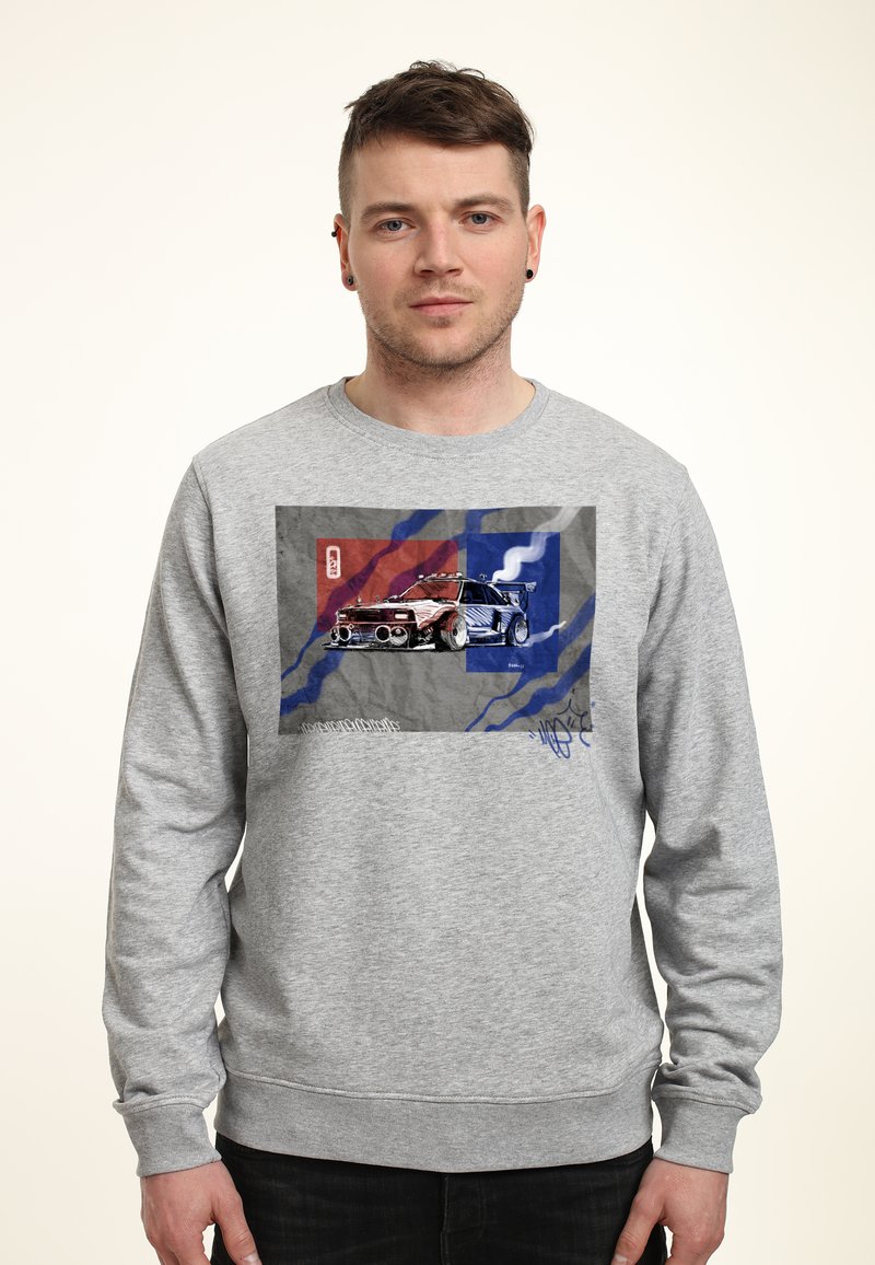 Sudadera gris con un estampado gráfico de un coche de carreras sobre un fondo texturizado con acentos en rojo y azul. Puños y dobladillo acanalados.