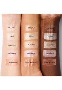 Cinq échantillons de maquillage étiquetés sur des teintes de peau claires, moyennes et foncées montrant les nuances : Moonlit, Eros, Electra, Heavenly et Total Eclipse.