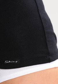 Schwarze Baumwollshorts mit einer glatten Textur, ausgestattet mit einem weißen Innenfutter und einem kleinen Markenetikett am unteren Rand.
