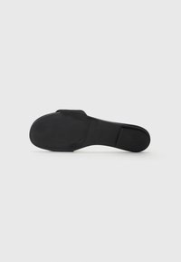 Svart sandal med en platt gummisula och ett brett rem överst. Slät yta, minimalistisk design utan ytterligare mönster eller accenter.