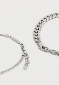 Δύο βραχιόλια από αλυσίδα ασημένια, με κούμπωμα σε σχήμα αστακού σε λευκό φόντο, το ένα με λείο σχέδιο επίπεδων συνδέσμων και το άλλο με παχιά αλυσίδα curb.