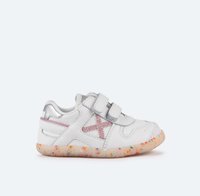 Zapatillas blancas para niños con detalles plateados, dos correas de velcro, costuras rosas en un diseño de X y una suela translúcida con manchas.