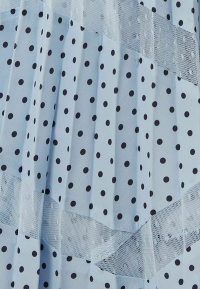 Tessuto azzurro chiaro con pois neri e strati di rete bianca trasparente, disposti in sezioni piegate diagonalmente.