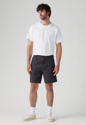 Witte katoenen t-shirt voor heren gecombineerd met grijze shorts. De shorts hebben een standaard pasvorm, een zachte textuur en een minimale afwerking.