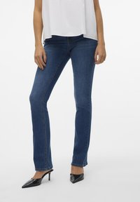 Mörkblå denimjeans med slim fit, med en midja i medelhöjd och diskreta söm detaljer. Kombineras med svarta klackskor med spetsig tå.