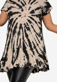 Sort og beige tie-dye tunika, korte ærmer, flagrende kant, let stof og slidte detaljer langs kanten.