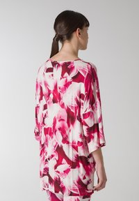 Lettet, flowy top i pink og hvid blomsterprint; har rund halsudskæring, trekvartærmer og løs pasform. Blødt, åndbart materiale.