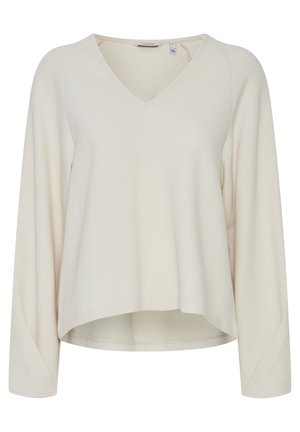 Svetlo béžový, dlhý rukáv, vrch s výstrihom do V, vyrobený z textúrovaného materiálu s jemným diamantovým vzorom a zakriveným lemom.