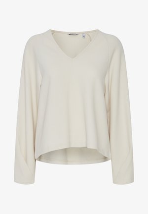 Svetlo béžový, dlhý rukáv, vrch s výstrihom do V, vyrobený z textúrovaného materiálu s jemným diamantovým vzorom a zakriveným lemom.
