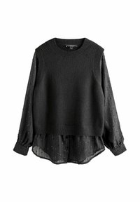 Pull sans manches noir en maille porté sur un chemisier noir transparent à manches longues avec sequins et détails de boutons, doté d'un col rond.