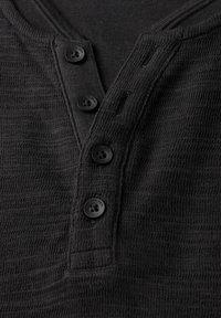 Svart strukturerad henley-skjorta med V-ringning, med fyra svarta knappar framtill och en ribbad krage.