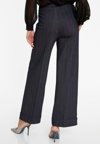 Donkerblauwe gestreepte wijde broek met een hoge taille, omslagen aan de hem, en een gladde textuur. Gecombineerd met hakken met een sprankelende afwerking.