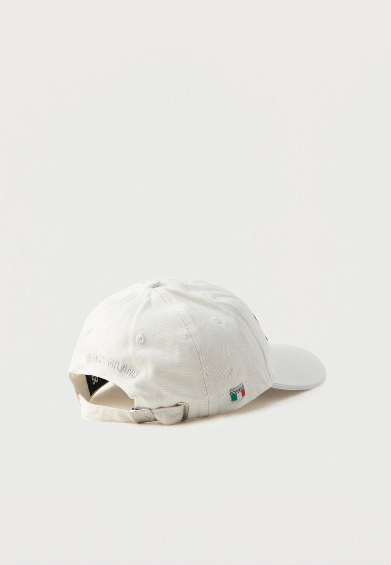 Casquette de baseball en coton blanc avec une visière arrondie, texte brodé à l'arrière et une petite étiquette avec le drapeau italien sur le côté.