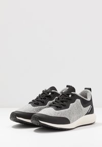 Baskets grises et noires avec une tige en laine texturée, des lacets noirs et une semelle blanche dotée d'une semelle extérieure en caoutchouc à motifs pour une meilleure adhérence.