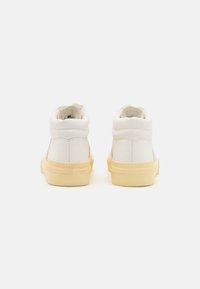 High-top sneakers in white leather with a yellow rubber sole. Features a padded collar and minimal stitching for a clean design.