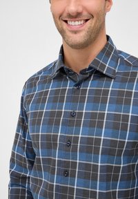 Camicia button-up grigia scura con un motivo a quadri blu. Caratterizzata da un colletto dritto e bottoni blu. Tessuto testurizzato per il comfort.