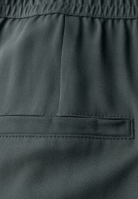Pantalon gris foncé en tissu texturé, avec une taille élastique, une poche arrière et un motif à côtes verticales subtil.