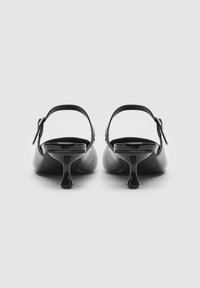Décolleté nere in pelle lucida con tacco curvo e cinturino regolabile. Il design presenta una superficie liscia e un'estetica minimalista.