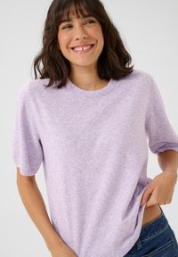 Pull court lilas à manches courtes avec un col rond, texture douce et coupe décontractée, associé à un jean en denim bleu.