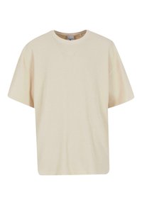 Tricou supradimensionat de culoare crem, cu o textură ribatată, decolteu rotund și mâneci scurte. Prezintă broderie discretă a logo-ului pe piept.