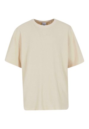 T-shirt oversize color crema con texture a coste, scollo rotondo e maniche corte. Presenta un ricamo del logo discreto sul petto.