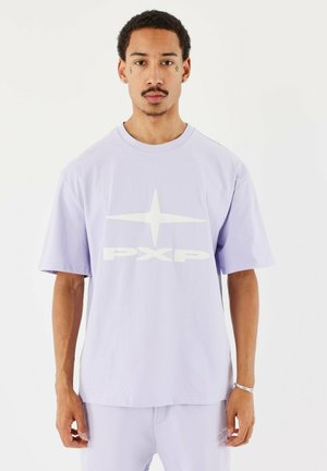 Lila oversized t-shirt van katoen met korte mouwen; heeft een grote witte graphic "PXP" en sterlogo op de voorkant. Zachte textuur.