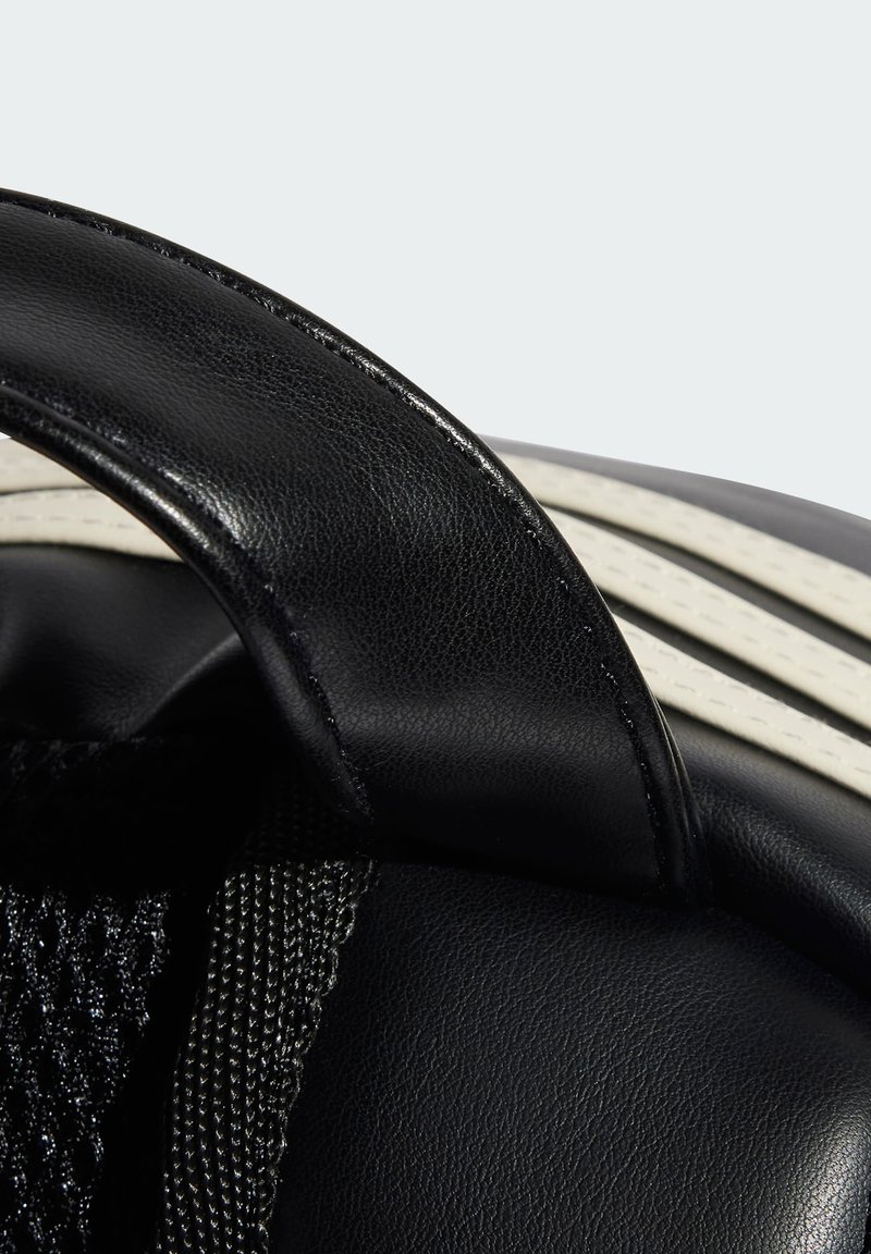 Sac en cuir noir avec une finition texturée, doté d'une poignée lisse et d'un accent en toile. Rayures blanches et détails en panneau en maille visibles.